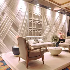 A chic photo-op or lounge area with a modern, textural white backdrop and elegant beige furniture. The arched niche and clean lines create a sophisticated setting for guest photos or a quiet conversation space.