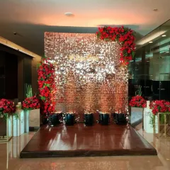 A glamorous anniversary setup with a rose gold sequin wall. The wall is framed with beautiful red roses, creating a dramatic and romantic photo backdrop.
