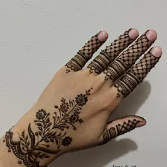 An elegant Arabic vine design that flows diagonally across the back of the hand. The pattern includes delicate floral motifs and fine latticework on the fingers, showcasing a light yet detailed style.