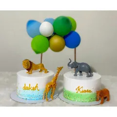 Celebrating twins with this elegant jungle-themed cake set. Each cake features a different animal friend, like a lion, giraffe, and elephant, with balloon toppers.