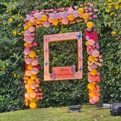 A photo booth is a must have for any birthday party. For this outdoor celebration, we created a beautiful photo frame surrounded by a lush arch of pink and yellow balloons and flowers, set against a natural green backdrop for perfect daytime pictures.