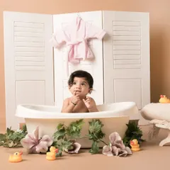 A thoughtful moment during a bathtub-themed shoot. The setup includes a vintage-style tub, floral decorations, and rubber ducks, creating a sweet and whimsical scene for a sitter session.