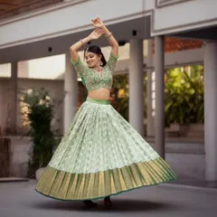 A vision of modern tradition, this Kanchi Pattu half saree in a vibrant pista green captures joyful movement. The pleated Kanchipuram silk skirt creates a beautiful flare, paired with a heavily embroidered blouse, making it a perfect choice for an engagement, sangeet, or half saree ceremony.