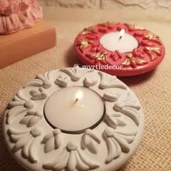 Our ornate, round tealight holders, shown here in classic white and a custom pink with gold detailing. These handmade Jesmonite pieces add a touch of elegance and festive warmth to your decor.