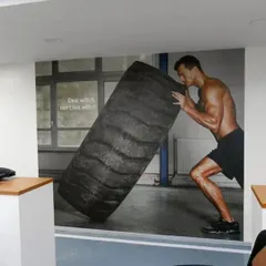 A custom wall mural of an athlete flipping a tire adds a raw, high-intensity feel to this fitness center. It’s a great way to define a functional training zone and motivate members during their workout.