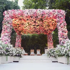 A breathtaking floral mandap designed for a romantic garden wedding ceremony. The structure is completely enveloped in thousands of fresh pink, peach, and ivory roses, creating a lush, fragrant, and unforgettable focal point for the couple's vows.
