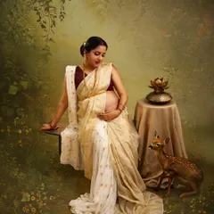 In this serene, Ravi Varma-inspired portrait, the mother-to-be is depicted with gentle grace. The soft lighting, traditional saree, and symbolic elements like the lotus and deer create a tranquil, artistic scene.
