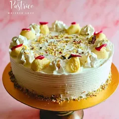 This is another take on my classic Rasmalai Cake, presented on a wooden stand. It highlights the creamy frosting, generous topping of homemade rasmalai, and a sprinkle of dried rose petals.