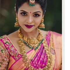 A striking close-up of a South Indian bride, showcasing her flawless makeup, intricate gold jewelry, and the vibrant colors of her wedding saree. Her confident gaze is captivating.