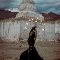 A warrior queen persona performing with fire fans against the ancient backdrop of a stupa. We use dramatic locations to enhance our fantasy narratives, blending history and myth with the elemental power of fire.