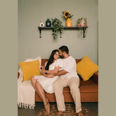 A comfortable and sweet embrace on the couch during an indoor pre-wedding shoot. The warm tones and home-like setup create a feeling of genuine intimacy.