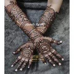 For your engagement, we can create a design that is both traditional and personal. This intricate mehendi features the couple's initials, 'ND', and interlocking rings, surrounded by classic peacock and floral motifs that extend up the forearm.