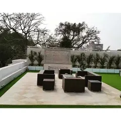 We designed this spacious terrace as an outdoor lounge. The area features a large seating arrangement on a paved section, surrounded by a pristine artificial lawn and a feature bonsai tree.