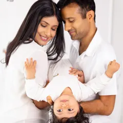 A playful moment during a family photoshoot, with parents holding their baby upside down. We mix posed shots with these fun, candid interactions to show your family's dynamic.