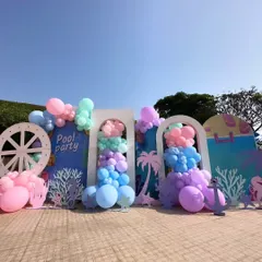 A wide view of the poolside party setup, showing how different elements come together. The custom backdrops, ship's wheel prop, and cascading pastel balloons create a cohesive and immersive environment for the celebration.