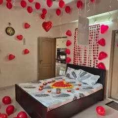 A classic romantic room surprise, perfect for anniversaries or just because. The decoration includes a heart made of flower petals on the bed, with red heart-shaped foil and latex balloons filling the room to create a warm, loving atmosphere.
