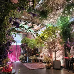 This wide view shows the enchanting atmosphere we created for the Arpita Mehta and Kunal Rawal event. We framed the space with an arch of greenery and purple flowers, using potted trees and warm string lights to transform the industrial brick venue into a magical, forest-like setting.