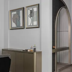 The entrance of 'Charcoal Chateau' sets a dramatic tone with a stunning arched mirror and curated artworks. This space is a harmonious blend of modern elements and artistic expression, offering a captivating welcome.