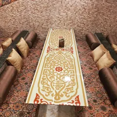 A high-angle view of my traditional Dastarkhwan seating. The ornate table design and comfortable floor cushions create an authentic and inviting atmosphere for a shared meal.