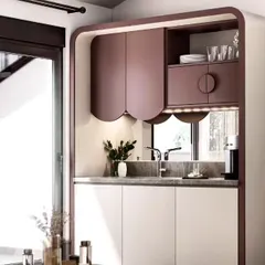 A modern and minimalist pantry or bar nook design. The unit features curved cabinet doors in a lovely mauve color, with integrated lighting and a small sink.