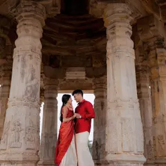 A couple stands between the ancient, carved pillars of a temple mandapam in Melukote, their connection as strong and timeless as the structure around them. A classic heritage pre-wedding photograph.