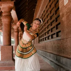 This shot captures a dancer in mid-pose, showcasing the dynamic movement and expressive nature of Mohiniyattam. The architectural lines of the corridor frame her beautifully.