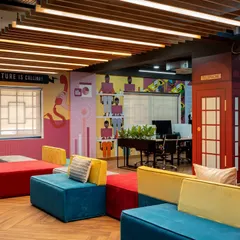 Workspaces should be fun. For this tech office, we created a vibrant breakout area with colorful modular seating, custom wall graphics, and a classic red London phone booth for private calls, injecting energy and brand personality into the workplace.