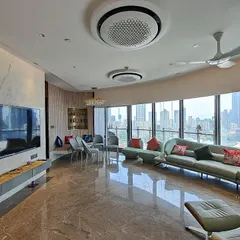 For the Jesrani Residence, the client requested a minimalist aesthetic. We designed this expansive living room to feel calm and uncluttered, using a gentle color scheme and a curved sofa that follows the building's form, all while maximizing the stunning panoramic city views.