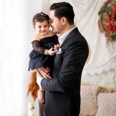 A proud father holds his daughter in this sweet and simple portrait. The focus is entirely on their loving bond.