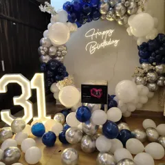 A stylish 31st birthday party decoration using a navy blue, silver, and white color scheme. The full balloon ring and light-up numbers create a fantastic photo opportunity.