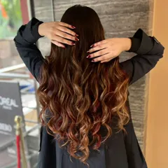 A stunning example of our hair coloring work. This client got a beautiful balayage with shades of brown and hints of red, styled into perfect waves.