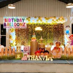 Here is another Cocomelon themed party, this time with a natural leaf wall backdrop and gold balloons. The setup includes cutouts of all the main characters, a personalized chalkboard-style milestone board, and a picket fence for a playful touch.