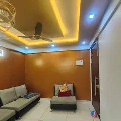 A living room featuring a warm, copper-toned metallic texture on the walls. This finish, combined with the false ceiling lights, creates a cozy and luxurious ambiance.