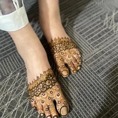 A delicate and simple henna design for feet, featuring a floral band across the top of the foot and detailed toe work.