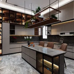 This kitchen in Alameda, Gurgaon, is the heart of the home, combining function with high-end aesthetics. It features a large marble-topped island with seating, extensive custom cabinetry for smart storage, and a suspended shelving unit with integrated planters, blending utility with a touch of nature.