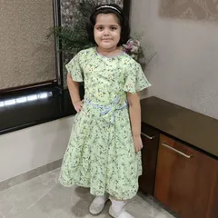 A happy girl posing in her light green floral dress. The flutter sleeves and simple tie-belt make this a comfortable and charming choice for everyday wear.