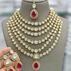 A similar multi-layered kundan necklace, this one featuring a vibrant ruby-red pendant and earrings.