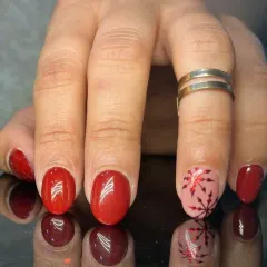A festive red manicure with a pink accent nail featuring a shiny red snowflake design.