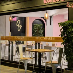 The outdoor seating area at Qoqobae, designed for customers to enjoy Bengaluru's pleasant weather. This space extends the cafe's footprint and enhances its street presence, making it a visible and active part of the neighborhood.