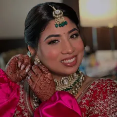 A happy smile from my bride Hiral as she puts on her earrings. I used warm tones and a soft contour to enhance her features for her Pheras.