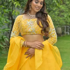 A candid shot of a model in the yellow lehenga, looking down with a smile. This shows the outfit and jewellery in a more natural, relaxed pose.