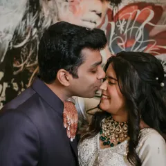 A sweet and candid moment with a gentle kiss on the cheek against a backdrop of modern art. The genuine smile is what makes this engagement photo so special.