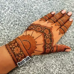 A trendy and modern design on the back of the hand. It features a semi circular mandala and a floral cuff, with detailed patterns on the fingers.