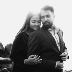 A beautiful black and white portrait against a bright, blown-out sky. The contrast creates a dramatic effect, focusing all the attention on the couple's gentle embrace and serene expressions.
