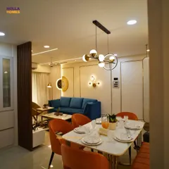A complete view of an open-plan living and dining area. We used a bold color palette with orange chairs and a blue sofa, balanced by a marble-top dining table and modern lighting to create a vibrant, cohesive space.