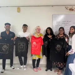 A group showing off their finished bleach art t-shirts. The contrast of the design on the dark fabric is so striking.