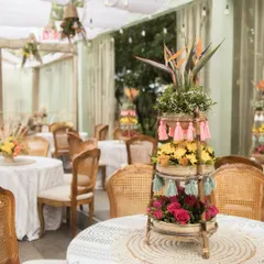 Our table centerpieces for the boho-themed Mehendi feature tiered bamboo stands decorated with colourful flowers and playful tassels. These details add a touch of whimsical charm and texture to the guest tables.