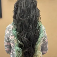 This back view shows a unique color combination of dark hair with mint green dip-dyed ends. The soft curls add a playful touch to this creative and eye-catching look.