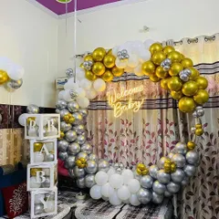A classic and elegant 'Welcome Baby' setup. The circular balloon arch in gold, silver, and white, along with the neon sign and 'BABY' blocks, creates a beautiful and celebratory backdrop for welcoming a new family member.