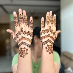 This is a lovely example of a modern, minimalist mehendi style. The design uses negative space with chevron patterns and delicate floral motifs near the wrist.